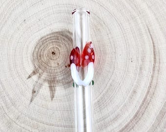 Può includere: Una cannuccia di vetro trasparente con un design a fungo. I funghi hanno cappelli rossi con pois bianchi e gambi bianchi. La cannuccia è decorata con piccole perle verdi.