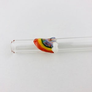 May include: A clear glass tube featuring a decorative accent piece shaped like a rainbow. The accent is crafted from multi-colored glass, displaying bands of red, orange, yellow, green, blue, and violet, finished with a solid white glass end.