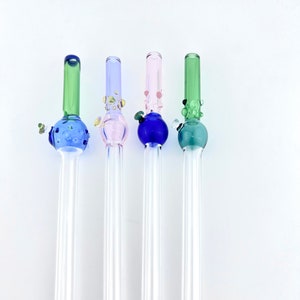 May include: Four glass drinking straws with colorful glass bulbs on the top. The bulbs are green, blue, pink, and teal. The straws are clear glass.