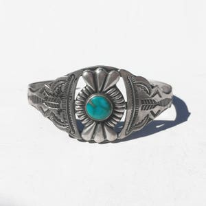 May include: A silver bracelet with a turquoise stone set in a floral design.