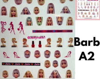 Könnte beinhalten: Eine Bogen mit Nagelaufklebern mit verschiedenen Barbie-Puppen-Gesichtern. Die Aufkleber sind rosa, weiß und blau. Der Bogen ist mit "Barbie A2" beschriftet.