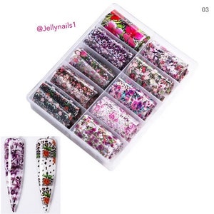 Puede incluir: Una caja de pl&aacute;stico transparente llena de 12 rollos de l&aacute;mina de transferencia para el arte de las u&ntilde;as. Cada rollo tiene un patr&oacute;n floral diferente en tonos de rosa, morado y verde. La caja est&aacute; etiquetada con el n&uacute;mero "03" y el texto "@Jellynails1".