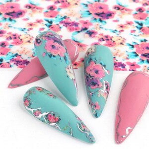 Puede incluir: Cinco puntas de u&ntilde;as largas y puntiagudas con un dise&ntilde;o floral. Dos puntas son de color turquesa con un patr&oacute;n floral plateado y tres puntas son de color rosa con un acento plateado.