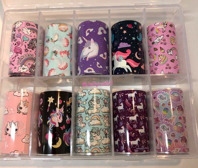 May include: A set of 10 unicorn-themed nail art foils in a clear plastic storage box. The foils feature various designs including unicorns, rainbows, stars, and hearts. The foils are in a variety of colours including pink, purple, blue, and black.
