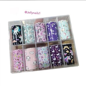May include: A clear plastic box containing 10 rolls of nail art transfer foil. Each roll features a different unicorn-themed design with colours like pink, purple, blue, and black.