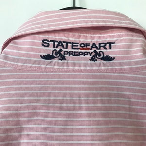May include: Pink and white striped button-down shirt with the text "STATE OF ART PREPPY" embroidered on the back collar.