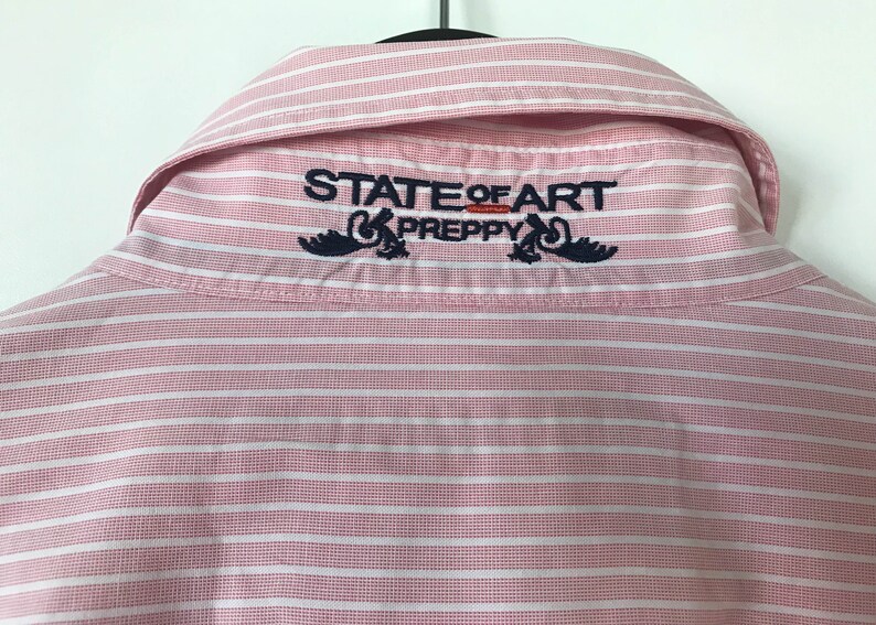 May include: Pink and white striped button-down shirt with the text "STATE OF ART PREPPY" embroidered on the back collar.