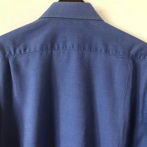 May include: A solid blue long-sleeved button-down shirt with a classic collar.