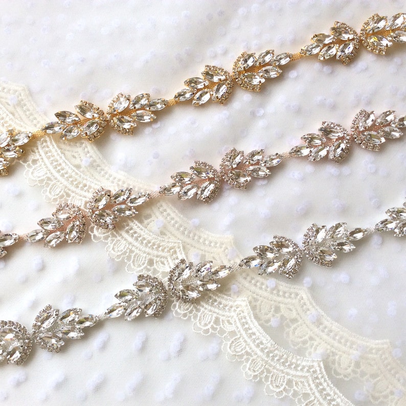 May include: Three rows of rhinestone trim with leaf-shaped embellishments. The top row is gold, the middle row is rose gold, and the bottom row is silver.