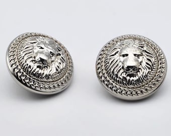 May include: Two silver-toned lion head buttons with a chain-link border. The buttons are round and have a raised lion head design.