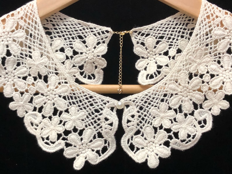 May include: White crocheted lace collar with a pearl button and a gold chain closure.