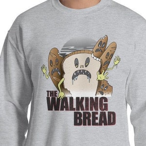 Puede incluir: Una sudadera gris con un gráfico de una hogaza de pan zombie con el texto "The Walking Bread" impreso en la parte delantera.