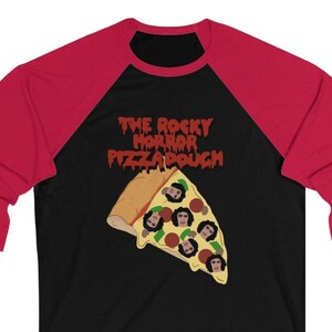 Peut inclure: Un t-shirt de baseball noir et rouge avec un graphique d'une part de pizza avec des visages de personnages du film "The Rocky Horror Picture Show" et le texte "The Rocky Horror Pizzadough".