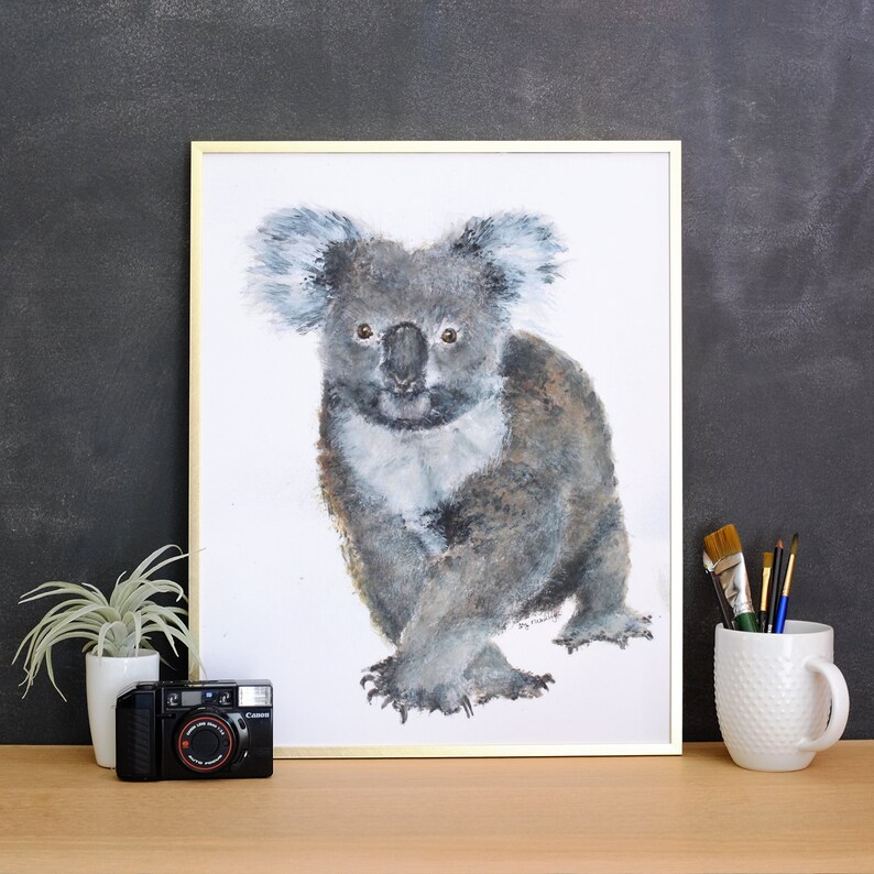May include: A framed watercolor painting of a koala bear in shades of gray, white, and brown. The koala is depicted with detailed fur and expressive eyes. The artwork is displayed with a gold frame.