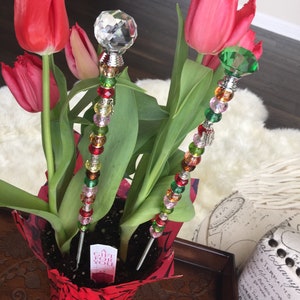 May include: A potted plant with red tulips and two decorative sticks with colorful beads and crystal accents. The plant pot is red with a white label that says "A Gift For You".