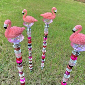 Pode incluir: Quatro estacas de jardim de flamingo rosa com contas de cristal e contas rosa, vermelhas e pretas. As estacas s&atilde;o de metal e t&ecirc;m um acabamento prateado.