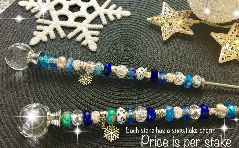 May include: Two silver snowflake themed stakes with crystal glass tops and blue and white beads. Each stake has a snowflake charm. "Price is per stake."