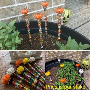 May include: A set of colorful beaded garden stakes with pumpkin-shaped tops. The stakes are made with various colored beads and have a metal base. The text "Price is per stake" is visible in the image.