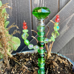 May include: A green glass cactus garden stake with a large green crystal on top and green, red, and iridescent beads.