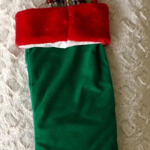 May include: A green Christmas stocking with a red and white cuff. The stocking is filled with colorful beaded wands with crystal tops.