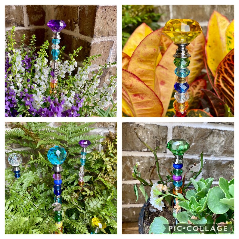 May include: Four colorful garden stakes with crystal tops and beads. The stakes are made of metal and have a variety of colors, including purple, yellow, blue, and green. The stakes are surrounded by plants.