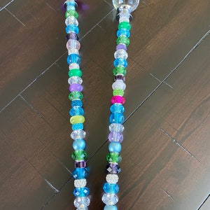 May include: Two decorative garden stakes with crystal tops and colorful beads. The stakes are made of metal and have a silver finish. The beads are in various colors, including blue, green, purple, and pink.