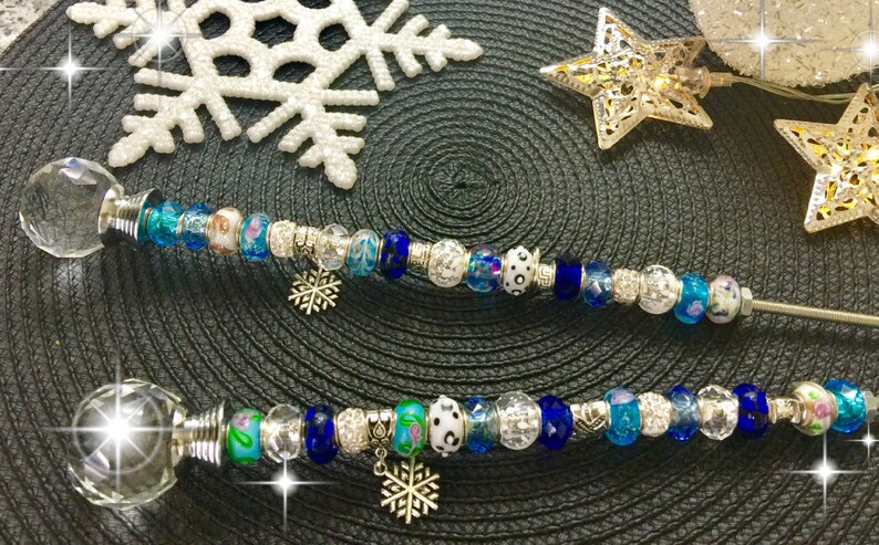 May include: Two crystal-topped wands with silver accents and blue, white, and silver beads. Each wand has a snowflake charm hanging from it.