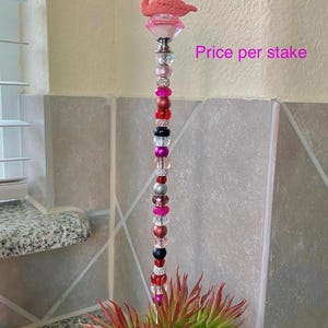 Pode incluir: Estaca de jardim de flamingo rosa com base de cristal e uma corrente de contas coloridas. Pre&ccedil;o por estaca.