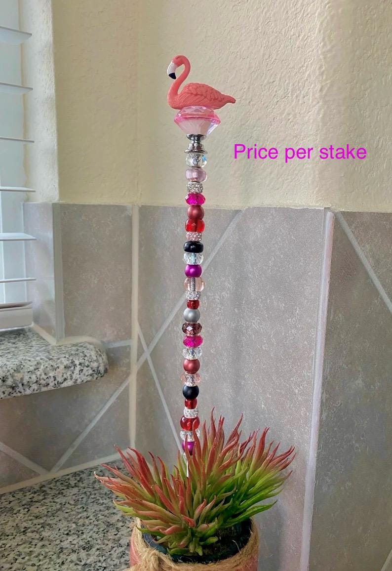 Pode incluir: Estaca de jardim de flamingo rosa com base de cristal e uma corrente de contas coloridas. Pre&ccedil;o por estaca.