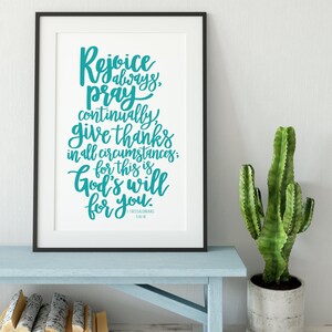 May include: A framed print with a teal blue inspirational quote: "Rejoice always, pray continually, give thanks in all circumstances; for this is God's will for you." The quote is from 1 Thessalonians 5:16-18.