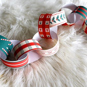May include: A paper chain with various Christmas-themed patterns. The chain links feature designs like candy canes, holly, plaid, and stripes in red, green, and white. The chain is displayed on a fluffy white surface.