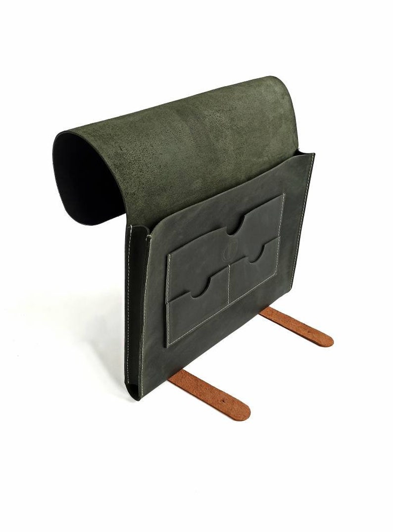 May include: A dark green leather portfolio with two pockets and brown leather straps. The portfolio is open and the inside is lined with a soft, dark green suede.