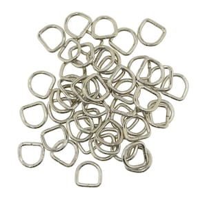May include: A pile of silver metal D-rings, commonly used for attaching straps, chains, or other hardware to bags, belts, or other items.