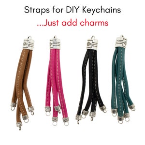 May include: Four leather keychain straps in brown, pink, black, and teal. Each strap has a silver-colored metal cap with a decorative design and a small ring for attaching charms. Text reads: Straps for DIY Keychains...Just add charms.