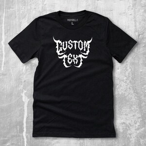 Puede incluir: Camiseta negra con el texto blanco "CUSTOM TEXT" en una fuente gótica estilizada. La camiseta de cuello redondo tiene una etiqueta de talla L. La marca "MOSHDOLlS" está impresa en la parte superior. Una prenda casual.