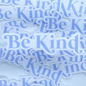 May include: A pile of light blue stickers with the text "Be Kind" on them. The stickers are arranged in a random pattern.