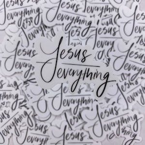 May include: A close-up of a pile of white stickers with black lettering that reads "Jesus Everything".