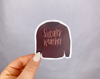 May include: A brown sweater sticker with the text "Sweater Weather" in gold lettering.