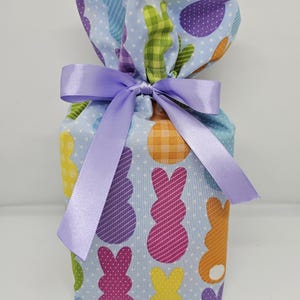 May include: A blue tissue box cover with a colorful Easter bunny pattern. The cover is tied with a lavender ribbon.