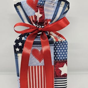 May include: A red, white, and blue fabric tissue box cover with a red ribbon bow. The fabric is a patchwork of stars, stripes, and hearts.