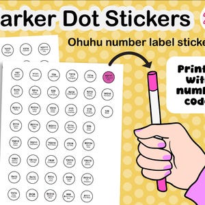 Op de afbeelding: Vellen marker dot stickers met kleurnamen en codes. De stickers zijn rond en wit met zwarte tekst. De afbeelding toont ook een hand die een roze marker vasthoudt, met de tekst "Gedrukt met nummercodes."