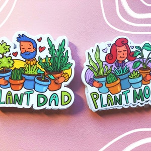 May include: Two stickers with cartoon illustrations of people holding potted plants. The sticker on the left says "Plant Dad" and the sticker on the right says "Plant Mom".