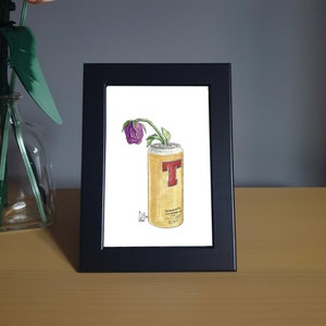 May include: A framed illustration of a wilted purple flower in a can of Tennent's Lager.