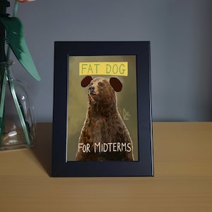 Può includere: Un'illustrazione incorniciata di un orso bruno con un cartello giallo sopra la testa che dice "FAT DOG FOR MIDTERMS!"
