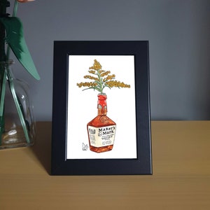 May include: A framed illustration of a bottle of Maker's Mark whiskey with a bouquet of yellow flowers in the bottle's neck.
