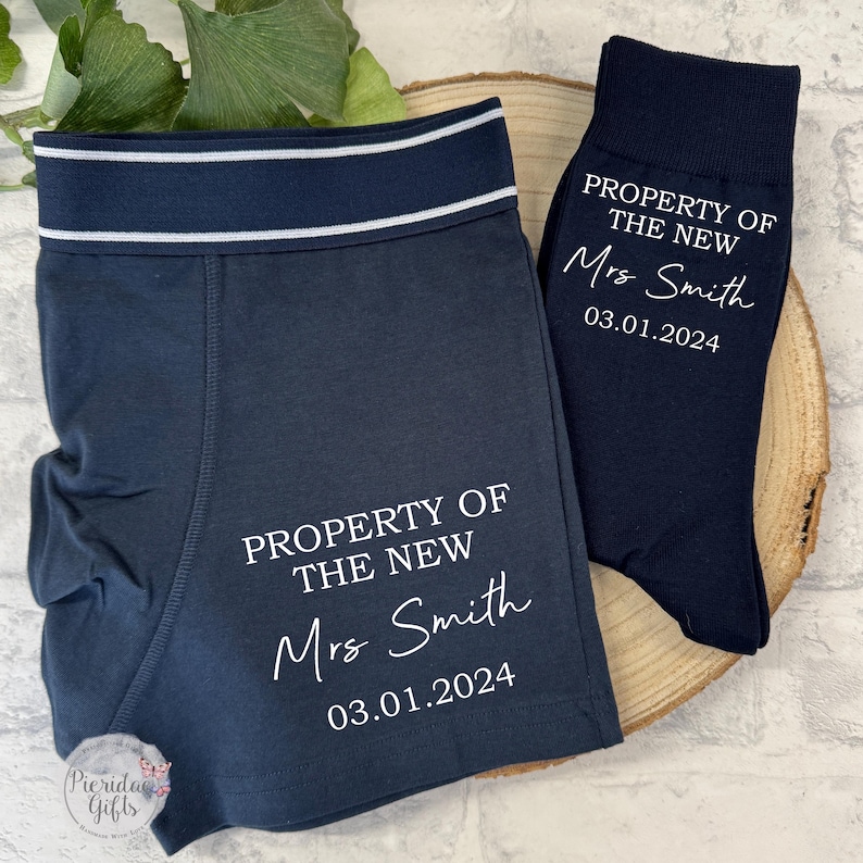 May include: A set of navy blue underwear and socks with white text that reads "PROPERTY OF THE NEW Mrs. Smith 03.01.2024".