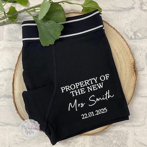 May include: Black underwear with white text that reads "PROPERTY OF THE NEW Mrs. Smith 22.01.2025".