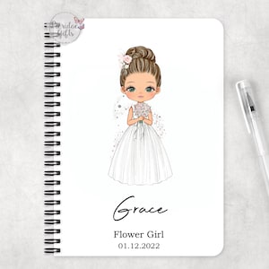 May include: A white spiral bound notebook with a cartoon illustration of a flower girl in a white dress holding a bouquet of flowers. The notebook has the name "Grace" written in cursive and the text "Flower Girl 01.12.2022".