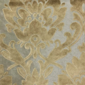 Pu&ograve; includere: Un tessuto caratterizzato da un motivo damascato beige in rilievo, simile al velluto, su uno sfondo di sottili linee diagonali grigio argento. La consistenza del motivo floreale beige contrasta con l'aspetto liscio e intrecciato della base.
