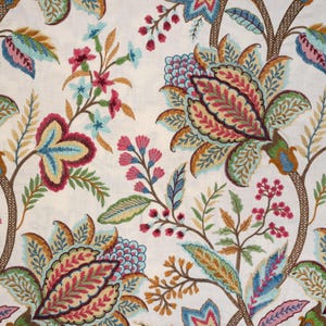 Puede incluir: Una tela blanca con un estampado floral colorido. El estampado presenta flores y hojas azules, verdes, rojas y marrones. La tela tiene un aspecto vintage y bordado.